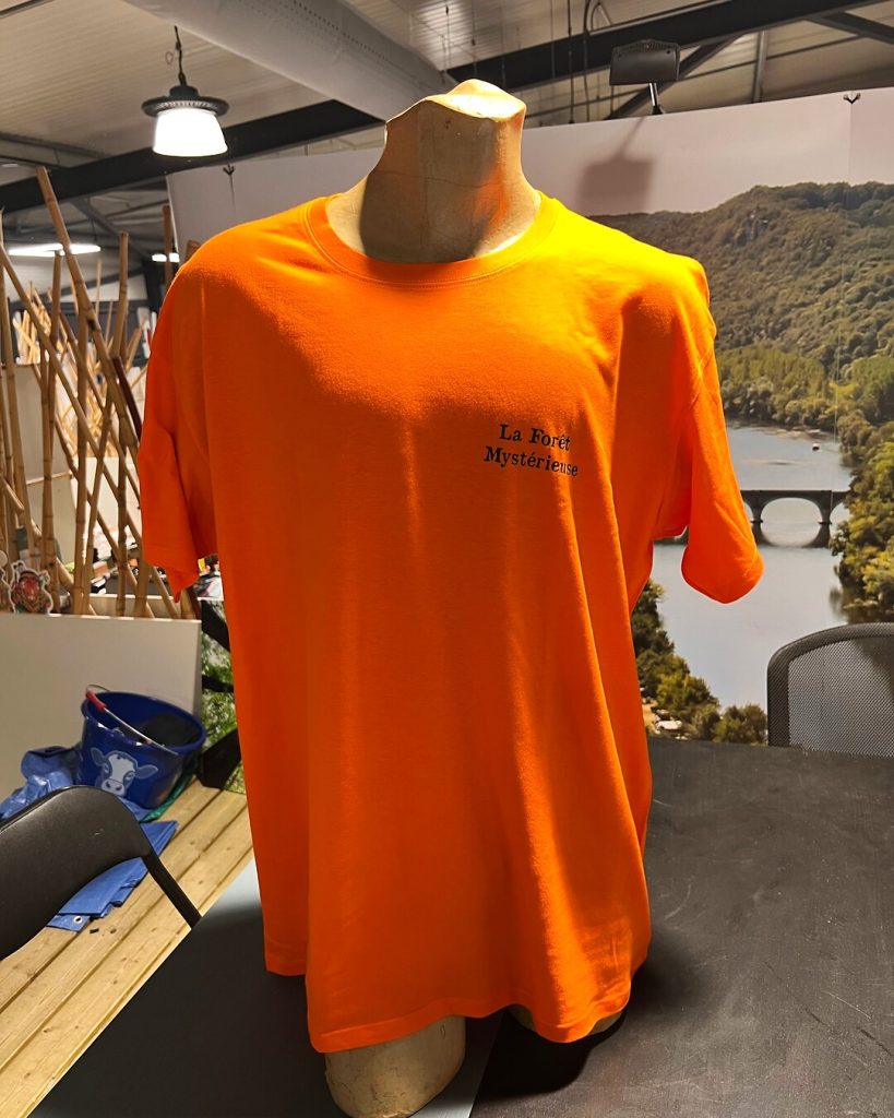 Face du t-shirt orange avec « La Forêt Mystérieuse » imprimé en noir côté cœur