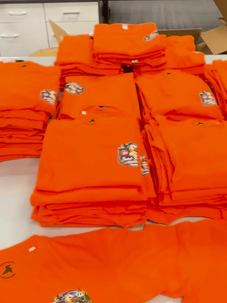 Les 140 tee-shirts orange de l'AS Saint-Joseph Sarlat pliés à l'atelier