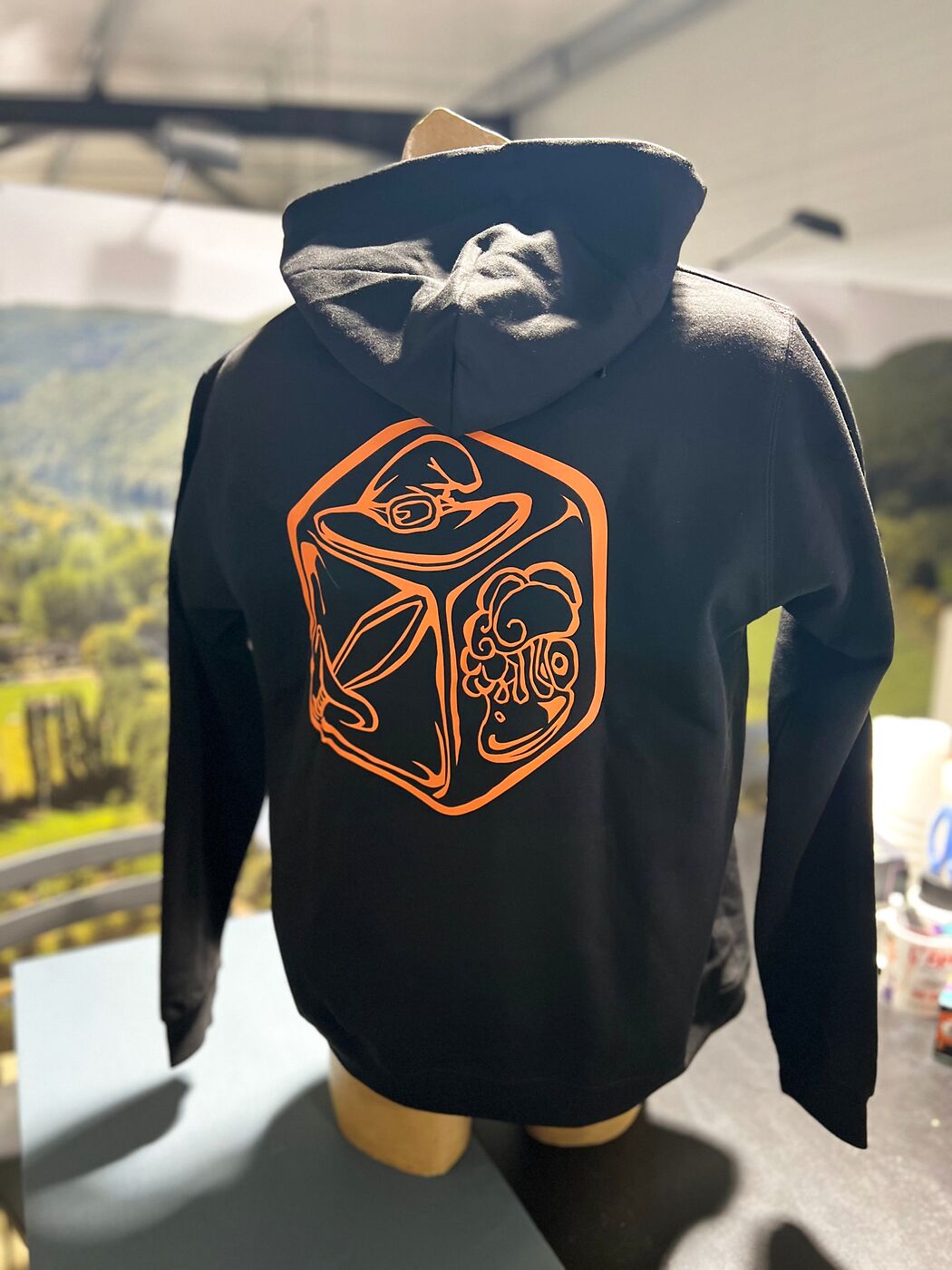 Dos du sweat à capuche noir de La Forêt Mystérieuse : dé avec chapeau de sorcier, épée et champignon imprimé en orange en DTF