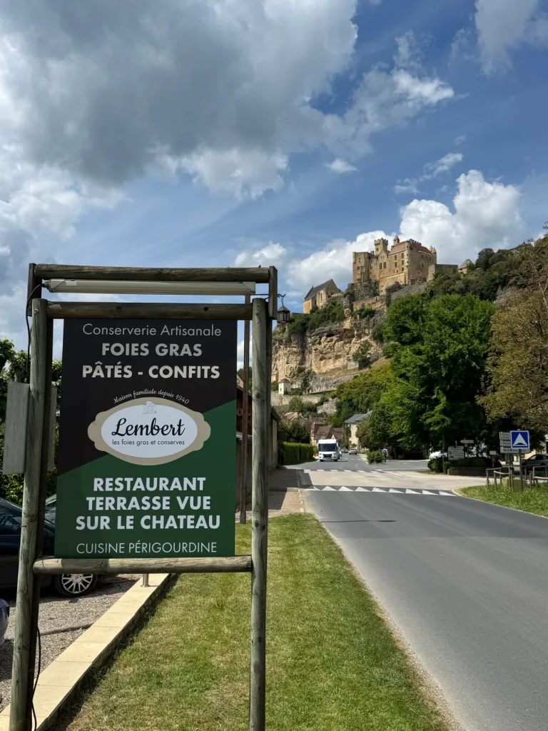 Panneau de bord de route de la Maison Lembert pour le restaurant et sa terrasse, avec le château de Beynac en arrière-plan