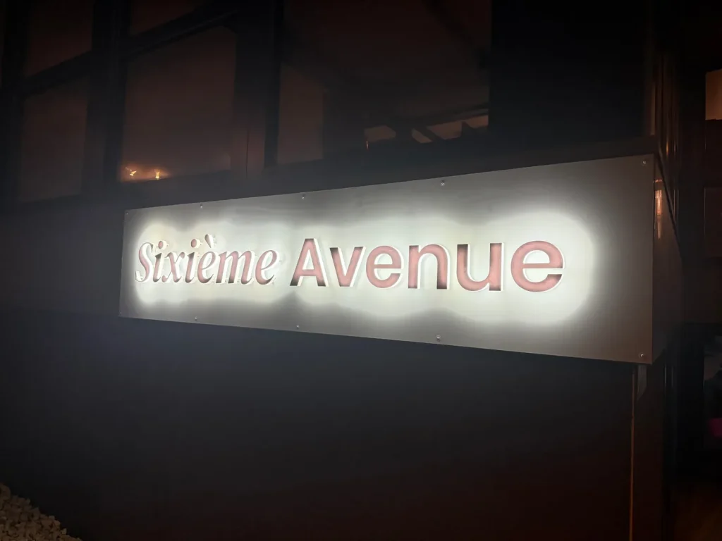Gros plan sur les lettres découpées en relief Sixième Avenue et leur halo lumineux LED